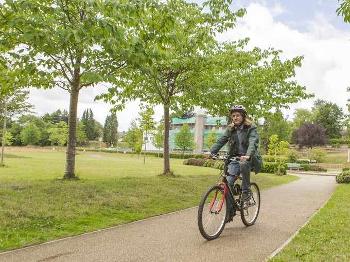student cycling through woods on path at Lampeter campus