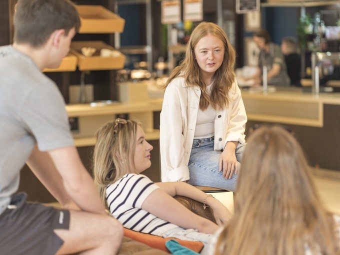 Students chatting on sofa in Merlin, Carmarthen