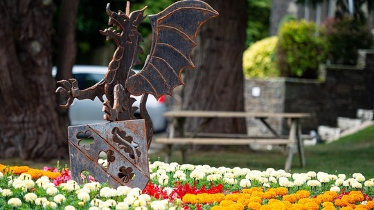 Metal sign of a Welsh Dragon surrounded by colourful flowers