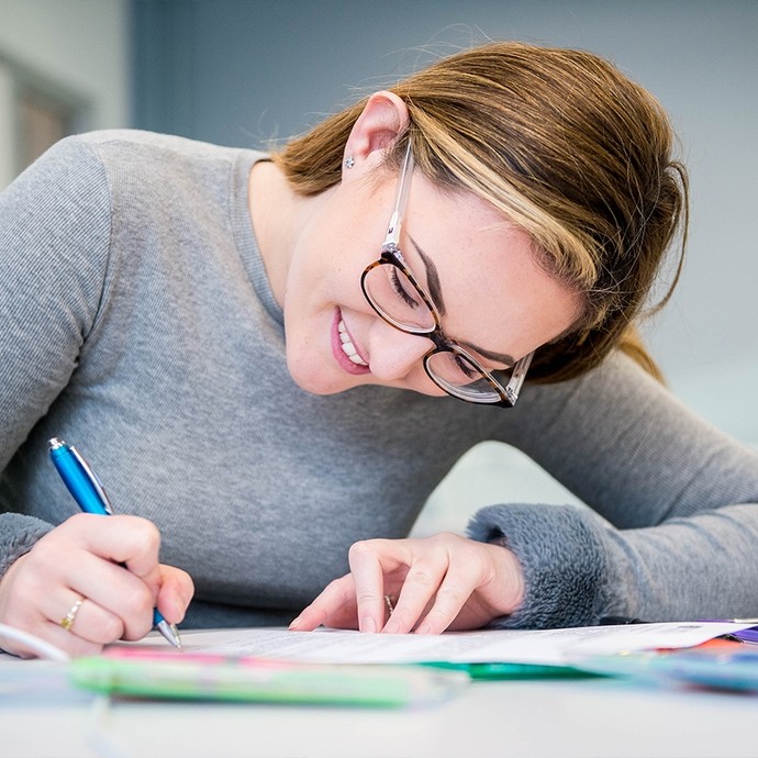 Student smiling and writing on a form