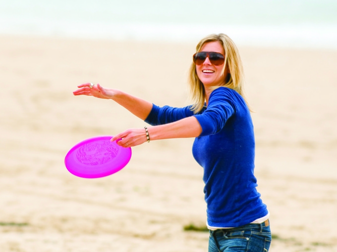 Student on Swansea beach throwing a frisbee