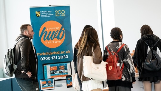Students standing next to a Student Hub banner