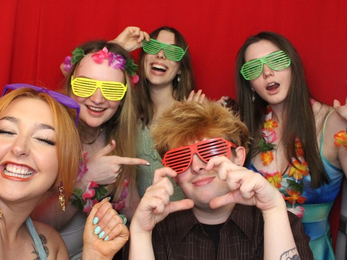 Group of students smiling and wearing colourful glasses