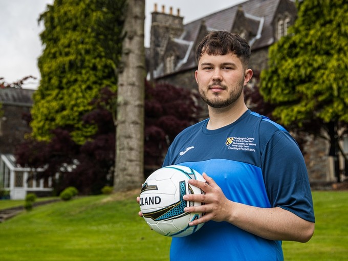 Student holding rugby ball outside the Carmarthen campus